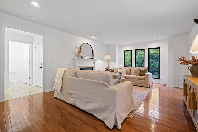9240 Shay Cv, Ooltewah, TN 37363 - living room featuring light wood-type flooring, a tiled fireplace, recessed lighting, and baseboards