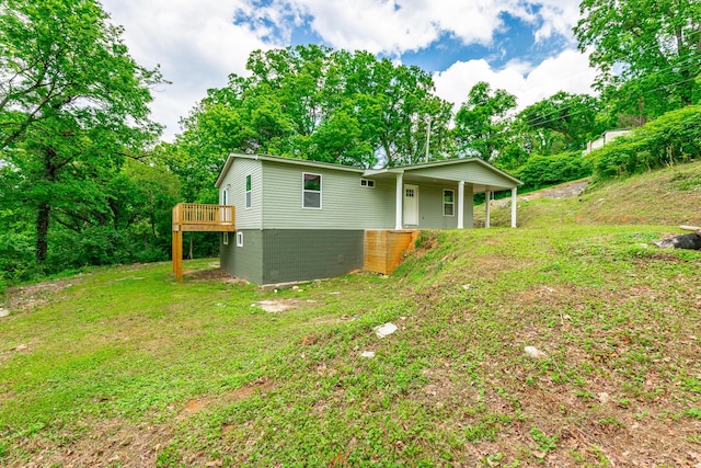 rear view of property featuring a lawn and a wooden deck