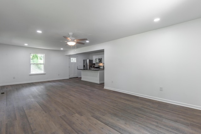 unfurnished living room featuring baseboards, dark wood-type flooring, and recessed lighting