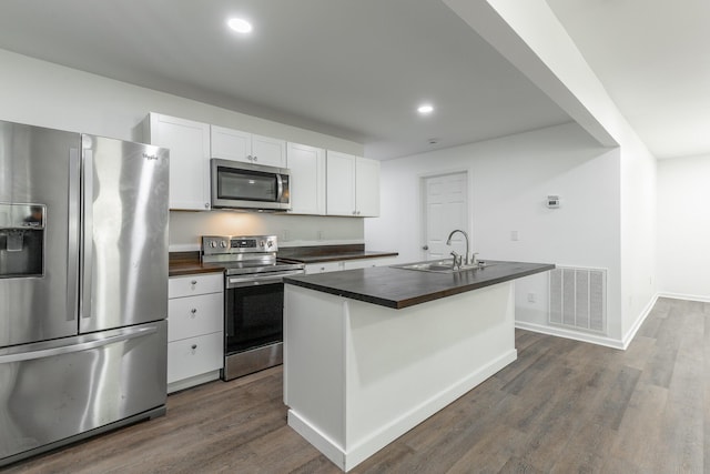 kitchen with a sink, stainless steel appliances, white cabinetry, and visible vents