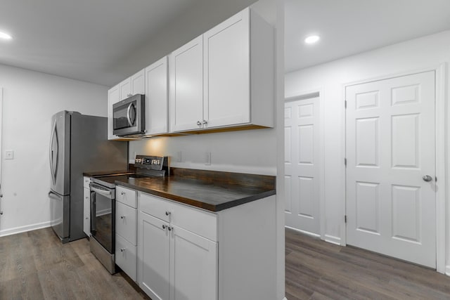 kitchen featuring wooden counters, white cabinetry, dark wood-style flooring, appliances with stainless steel finishes, and recessed lighting