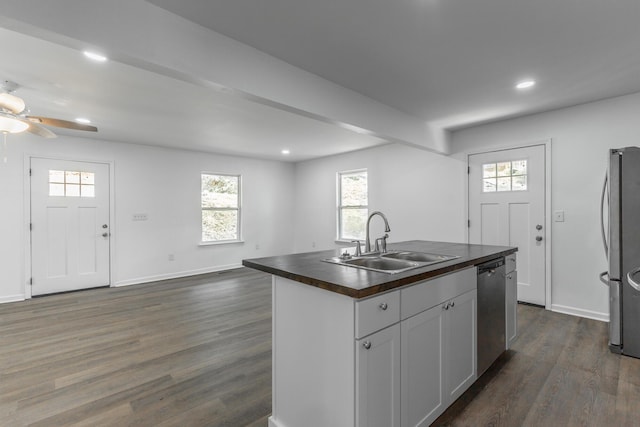 kitchen with a sink, a kitchen island with sink, ceiling fan, appliances with stainless steel finishes, and butcher block counters