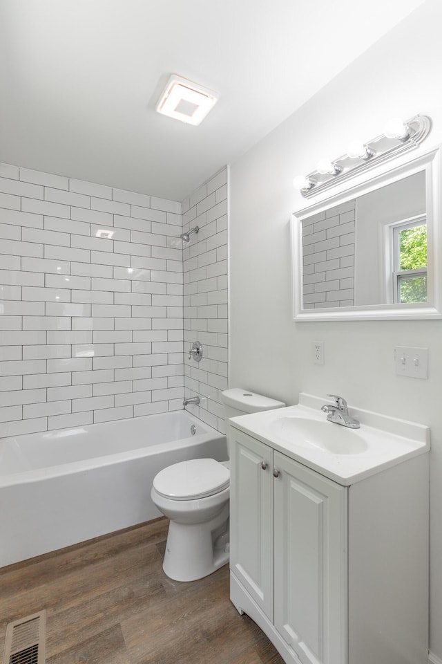 full bathroom with toilet, wood finished floors, vanity, visible vents, and  shower combination