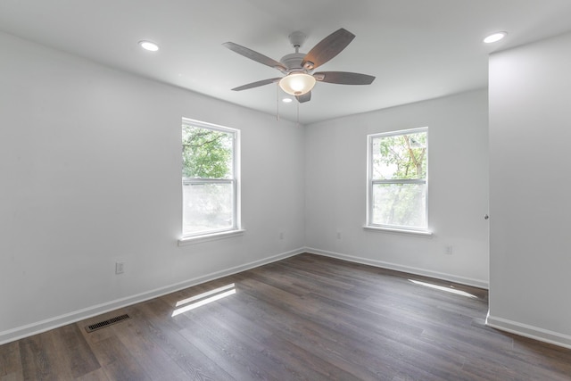 spare room featuring ceiling fan, dark wood finished floors, baseboards, and a healthy amount of sunlight