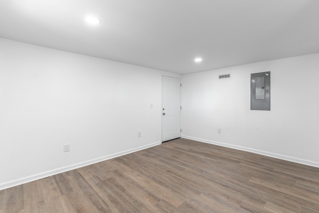 unfurnished room with wood finished floors, electric panel, visible vents, baseboards, and recessed lighting