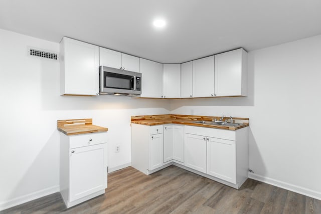kitchen featuring stainless steel microwave, a sink, visible vents, and wood finished floors