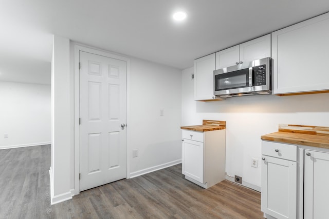 kitchen featuring white cabinetry, light wood finished floors, butcher block counters, and stainless steel microwave