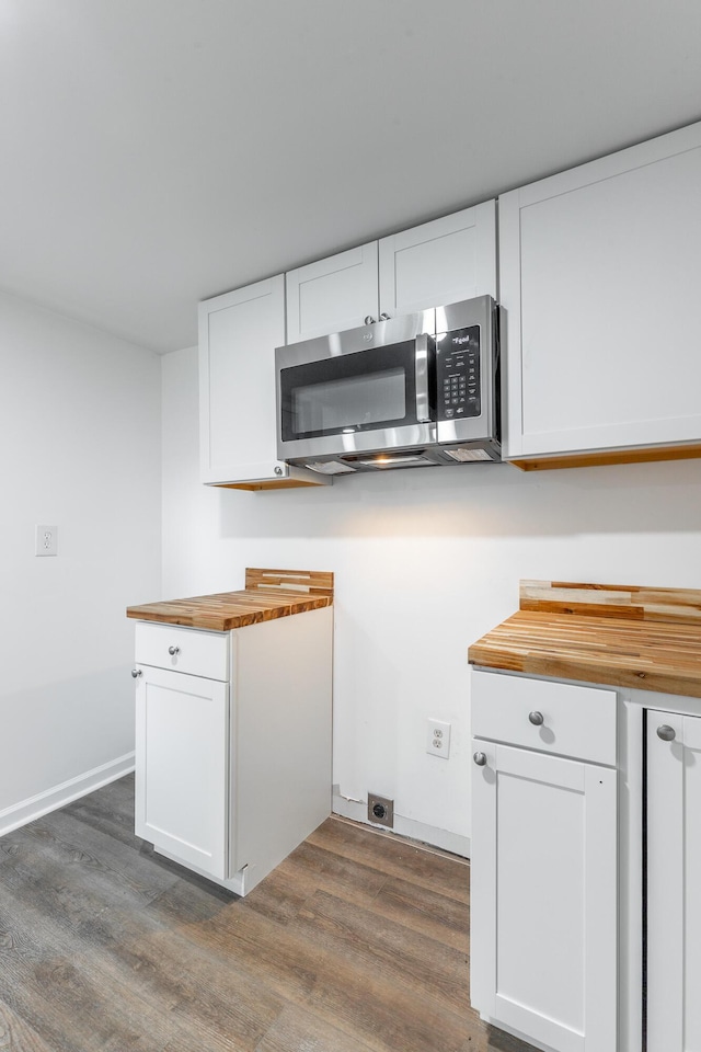 kitchen featuring stainless steel microwave, wooden counters, white cabinetry, and dark wood-style floors