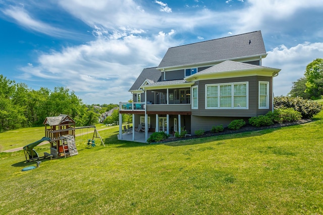 back of property featuring roof with shingles, a sunroom, a playground, a patio area, and a yard
