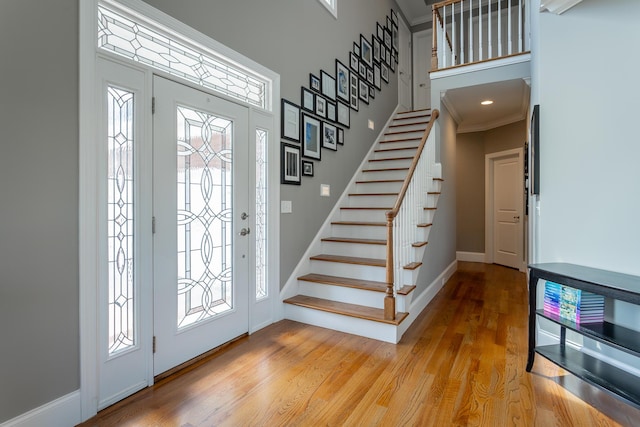 foyer with baseboards, stairs, light wood-style flooring, and a towering ceiling