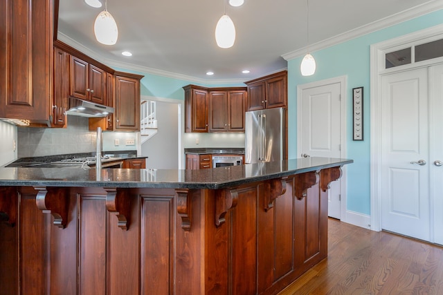 kitchen featuring ornamental molding, a peninsula, under cabinet range hood, tasteful backsplash, and high end refrigerator