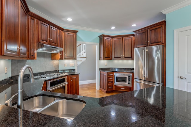kitchen featuring ornamental molding, under cabinet range hood, tasteful backsplash, a sink, and appliances with stainless steel finishes