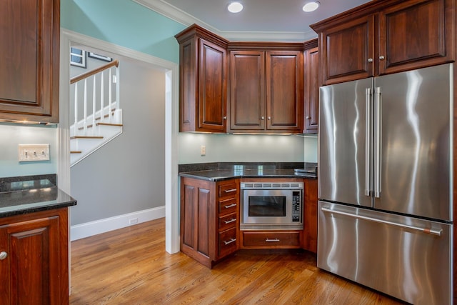 kitchen with appliances with stainless steel finishes, light wood-style flooring, dark stone counters, recessed lighting, and baseboards