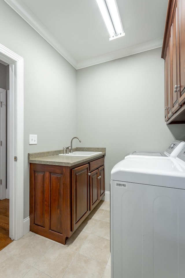 laundry area featuring a sink, ornamental molding, cabinet space, and washing machine and dryer