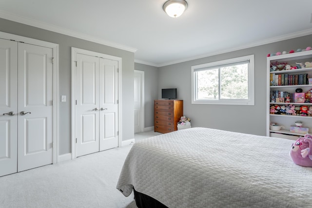 carpeted bedroom featuring baseboards, ornamental molding, and two closets