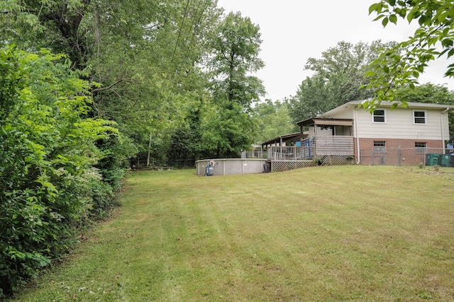 view of yard featuring an outdoor pool, a wooden deck, and fence