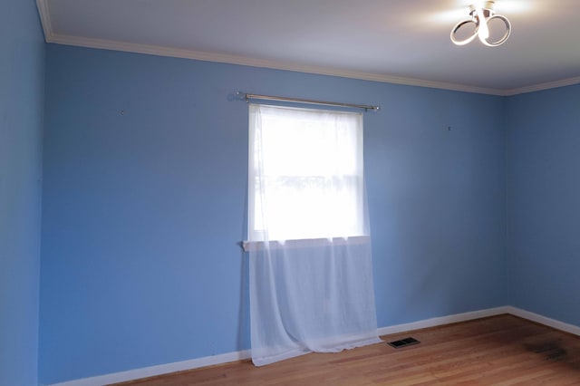 unfurnished room with baseboards, ornamental molding, wood finished floors, and visible vents