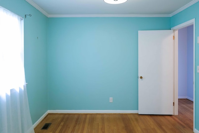 spare room featuring crown molding, baseboards, visible vents, and wood finished floors