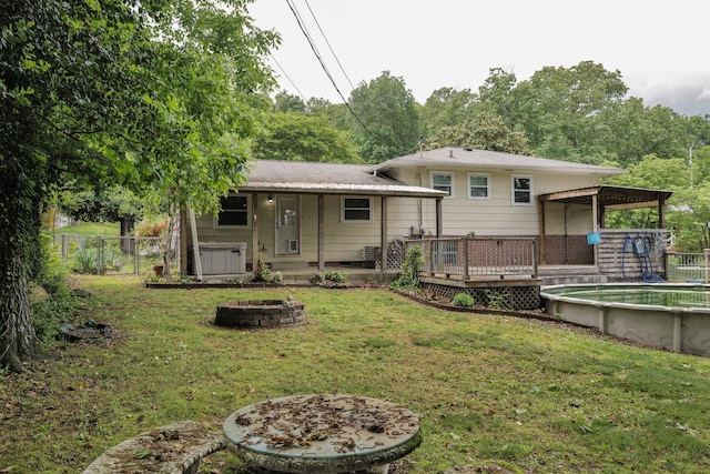 back of house with a yard, a wooden deck, a fenced backyard, and an outdoor fire pit