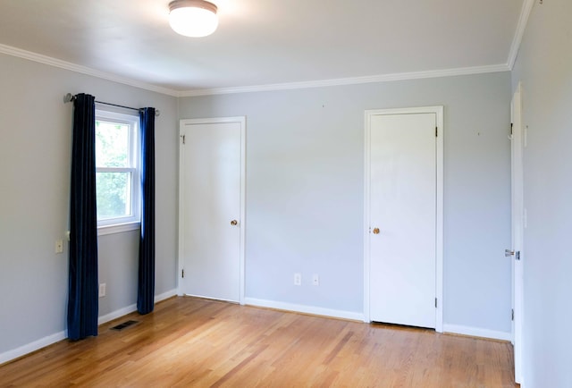 unfurnished bedroom with visible vents, crown molding, multiple closets, wood finished floors, and baseboards