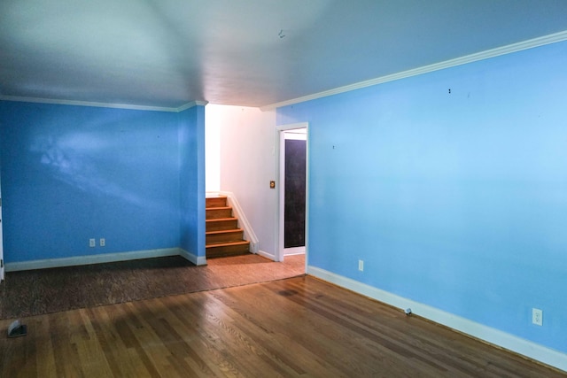 empty room featuring crown molding, baseboards, stairs, and wood finished floors
