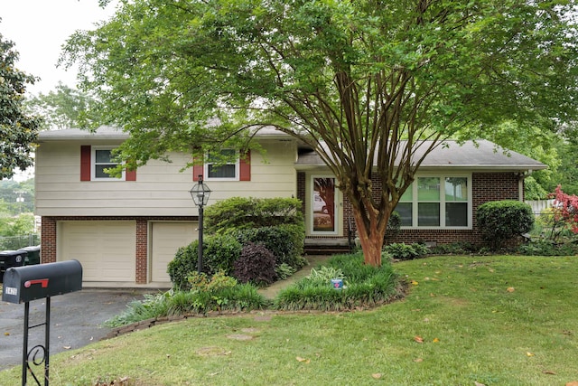 tri-level home with an attached garage, driveway, a front lawn, and brick siding