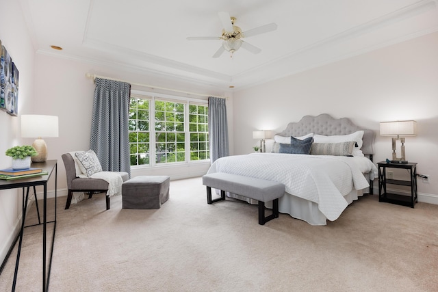 carpeted bedroom featuring a tray ceiling, crown molding, baseboards, and ceiling fan