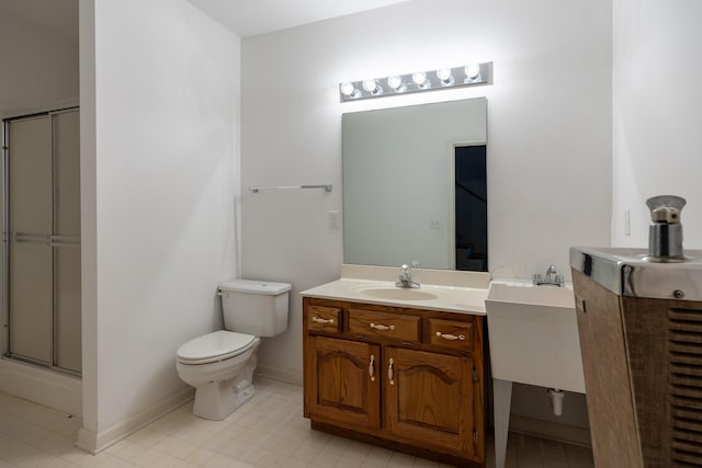 bathroom featuring a shower with shower door, baseboards, vanity, and toilet