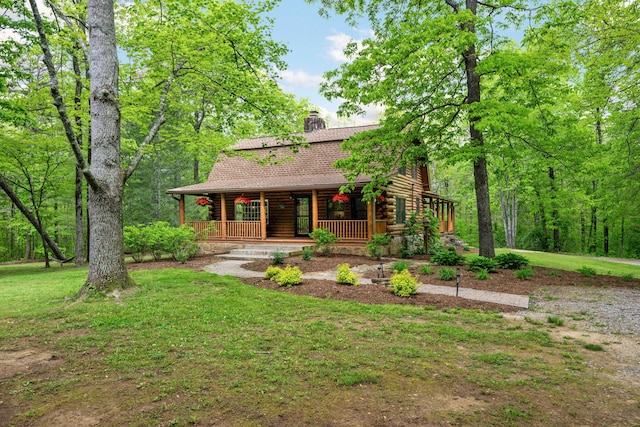 view of front facade with a chimney, a front yard, covered porch, and log exterior