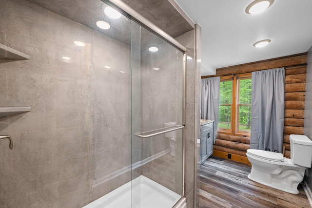 full bath featuring vanity, toilet, wood finished floors, and a stall shower
