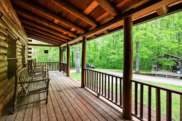 wooden deck with a gazebo and a view of trees