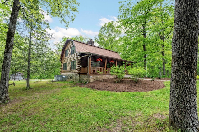 view of side of home featuring a lawn, roof with shingles, a chimney, log siding, and a porch