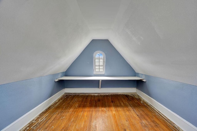 bonus room with wood-type flooring, lofted ceiling, and baseboards