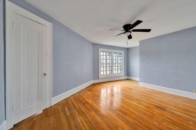 empty room with baseboards, light wood-type flooring, and ceiling fan
