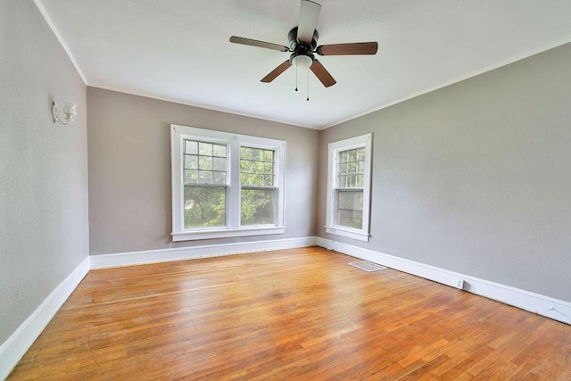 empty room with baseboards, a ceiling fan, ornamental molding, and wood finished floors