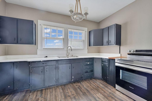 kitchen with electric stove, a sink, dark wood finished floors, light countertops, and decorative light fixtures