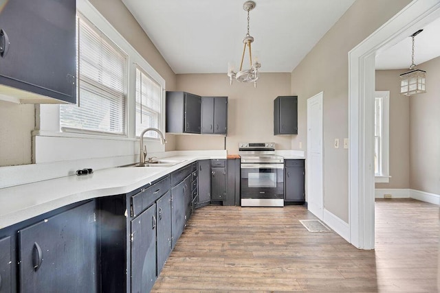 kitchen featuring electric range, a sink, light wood-style floors, a chandelier, and decorative light fixtures