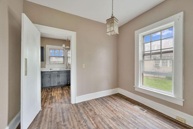spare room with a chandelier, healthy amount of natural light, and wood finished floors