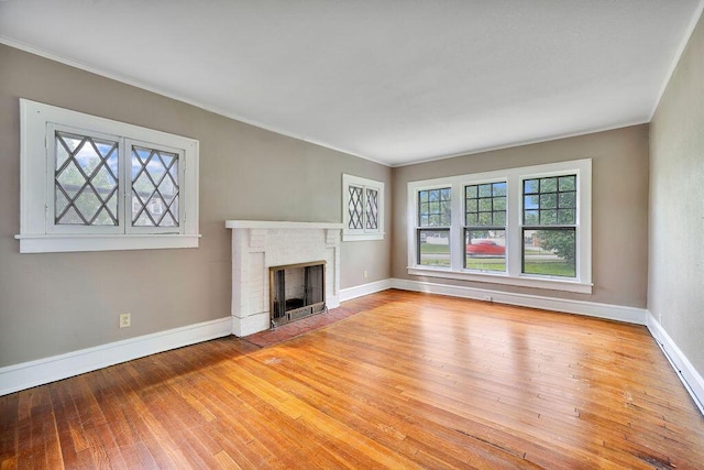 unfurnished living room featuring ornamental molding, baseboards, a fireplace, and hardwood / wood-style floors