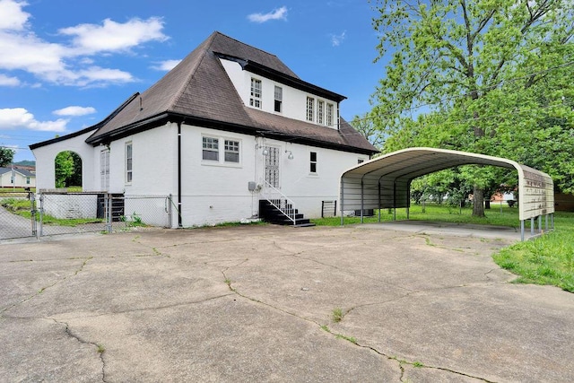 back of property with a gate, driveway, a detached carport, a shingled roof, and fence