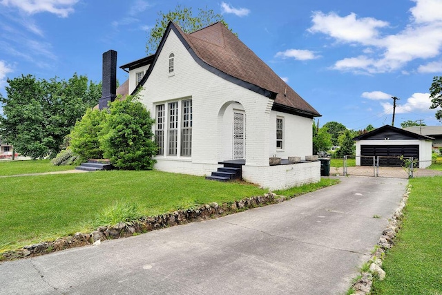 view of home's exterior featuring a chimney, brick siding, a gate, a detached garage, and an outdoor structure