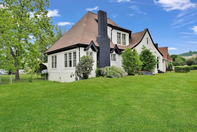 view of home's exterior featuring a lawn, a chimney, and roof with shingles