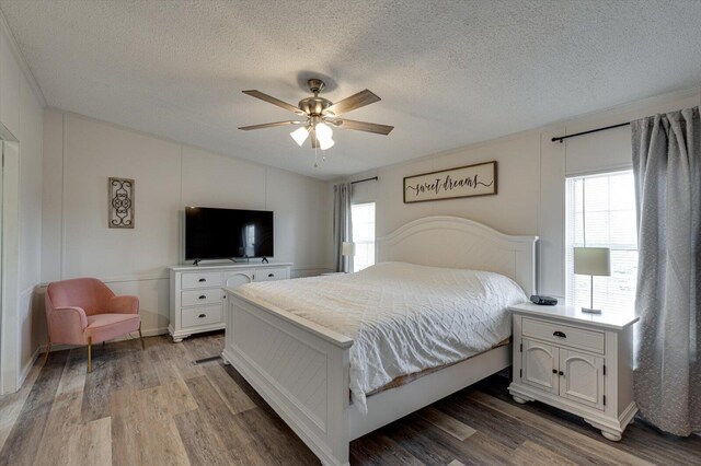 bedroom with vaulted ceiling, a textured ceiling, and wood finished floors