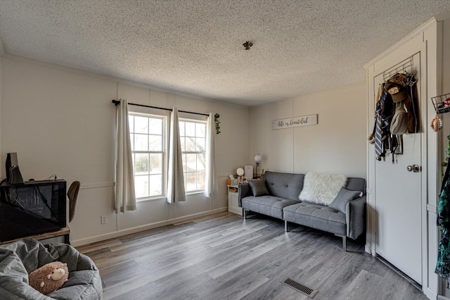 living room featuring visible vents, a textured ceiling, and wood finished floors