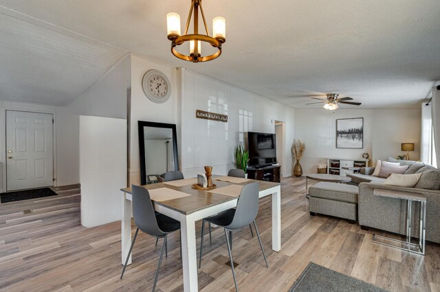 dining room with light wood-style floors and ceiling fan with notable chandelier