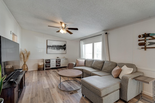 living room with a ceiling fan, a textured ceiling, light wood-style flooring, and lofted ceiling