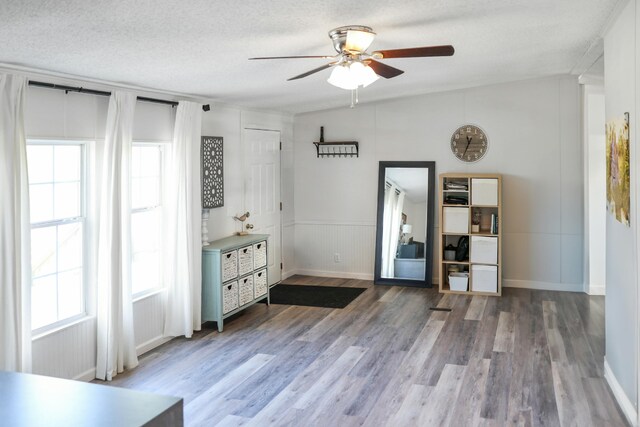 interior space with baseboards, a ceiling fan, a textured ceiling, and wood finished floors