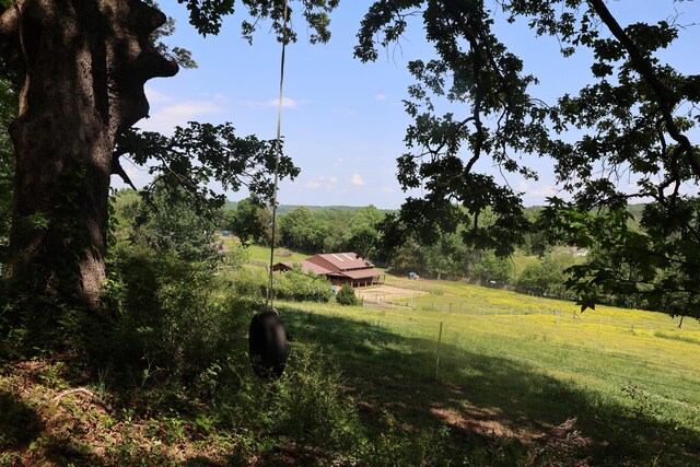 exterior space with fence, an outbuilding, and a rural view