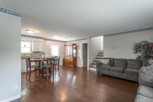 living area with baseboards, stairway, and dark wood-type flooring