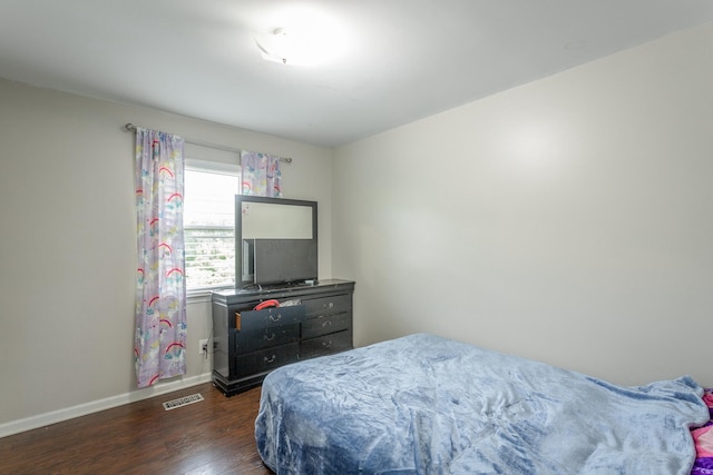 bedroom with baseboards, dark wood finished floors, and visible vents